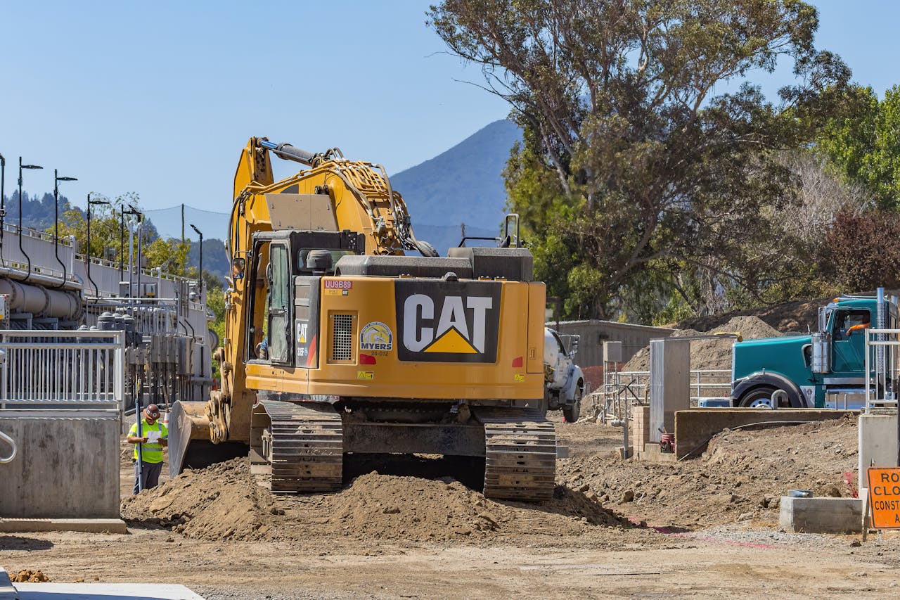 gallery-6 Excavator working at a construction site with mountains in the background.