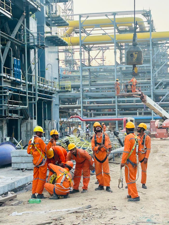 contact-img Group of construction workers in orange uniforms operating at an industrial site.