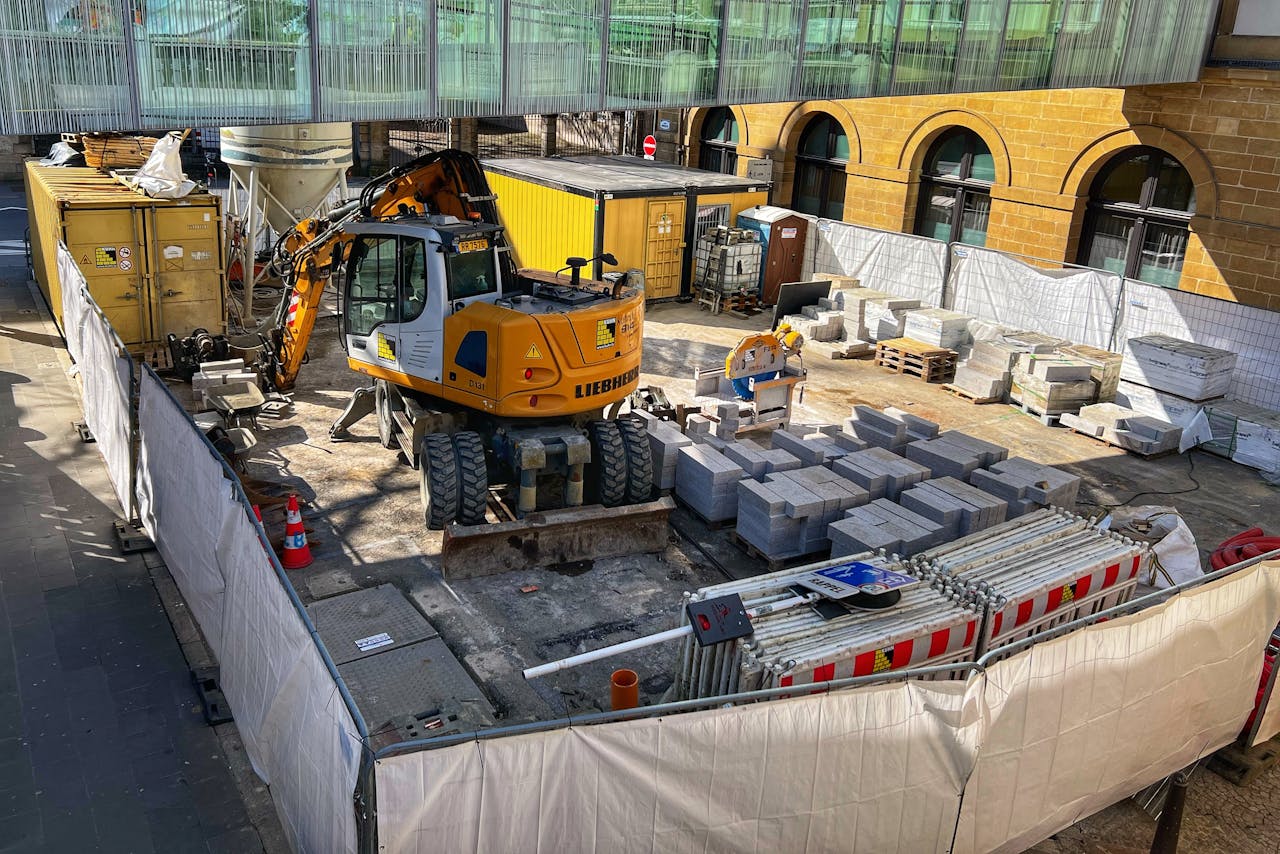 about-01 A construction site with machinery and materials in an urban setting during daytime.