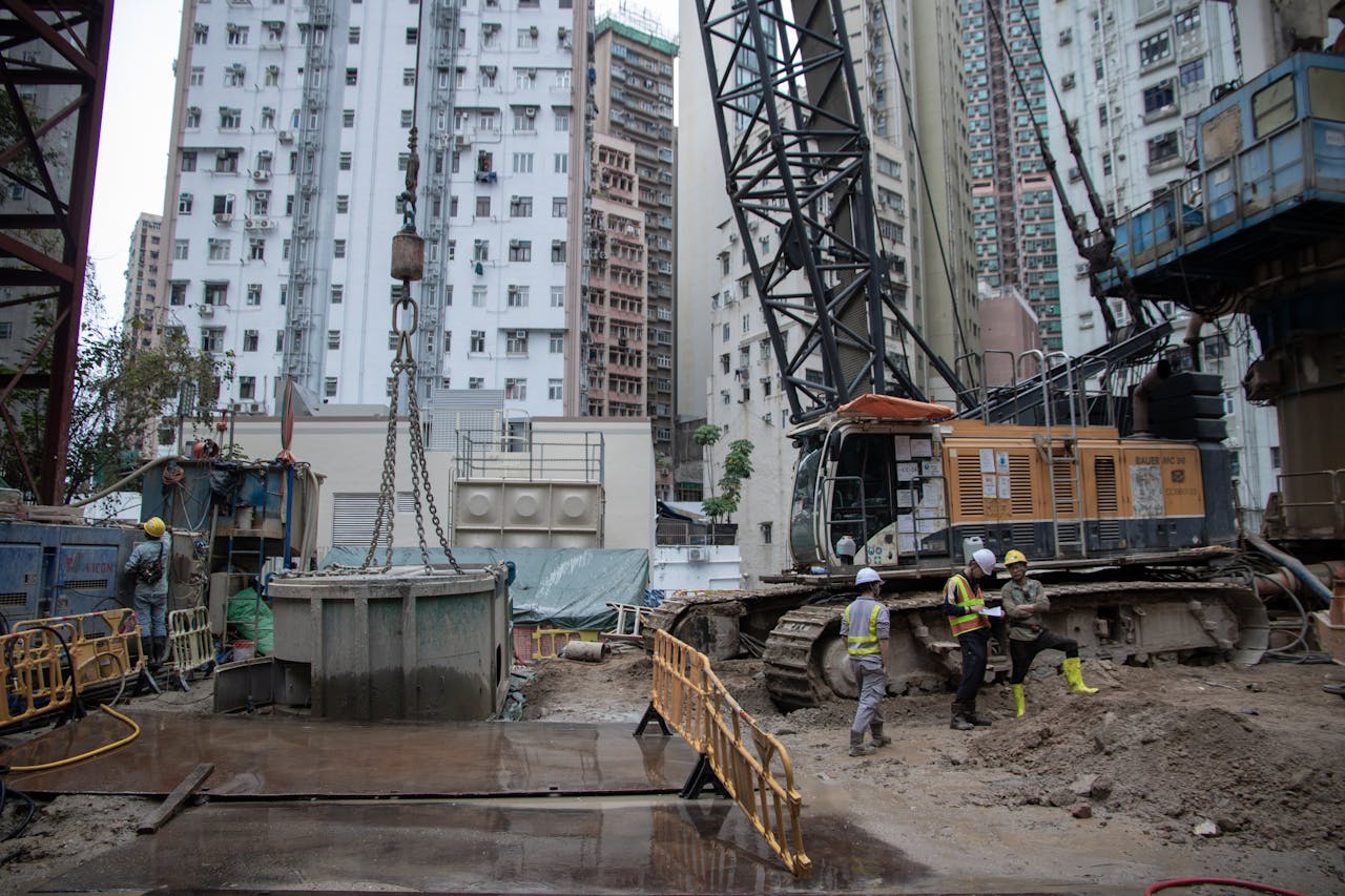 hero-img-02 City construction site with workers, cranes, and high-rise buildings.