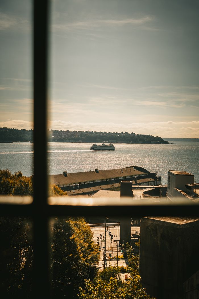 Serene view of a ferry crossing Puget Sound from Seattle waterfront window.