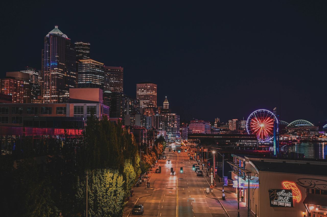 about-img Seattle's vibrant skyline and iconic Ferris wheel illuminated under the night sky.