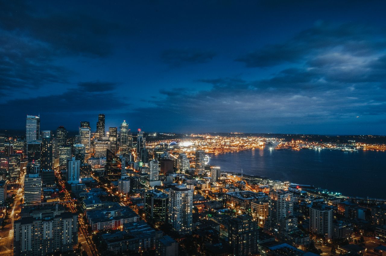 Aerial view of Seattle's illuminated skyline and waterfront at night.