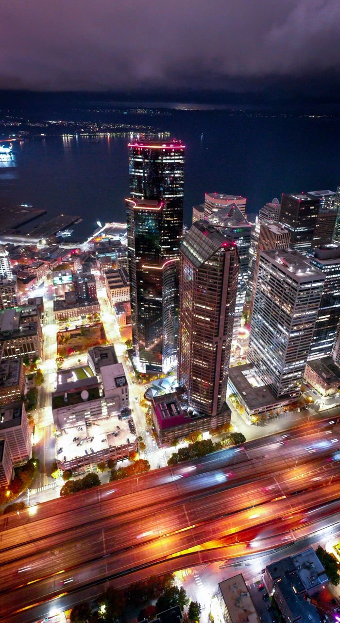 A captivating aerial view of Seattle's illuminated skyline with skyscrapers and vibrant city lights reflecting at night.